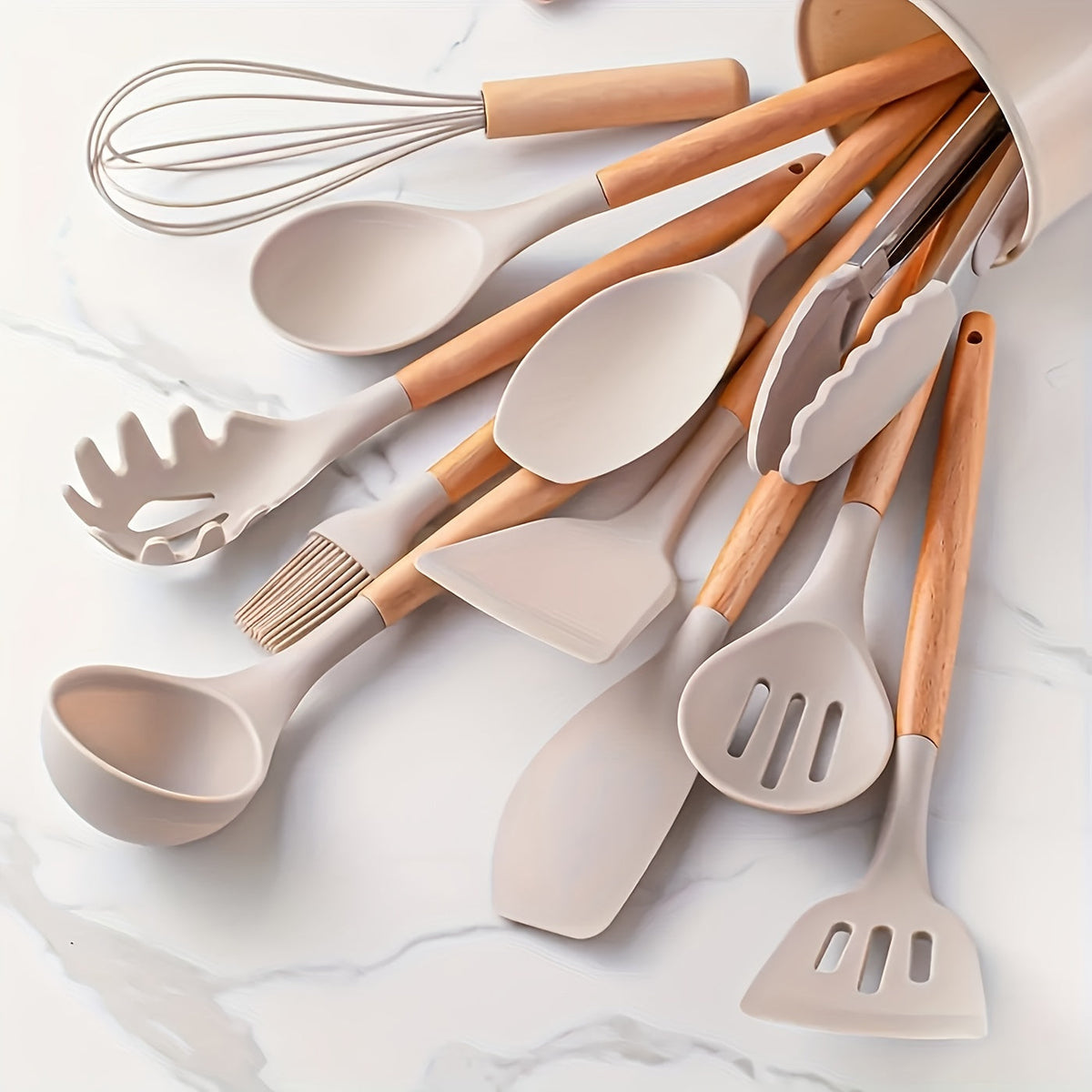 Silicone kitchen utensil set with light wood handles and white spatulas, spoons, and whisk.