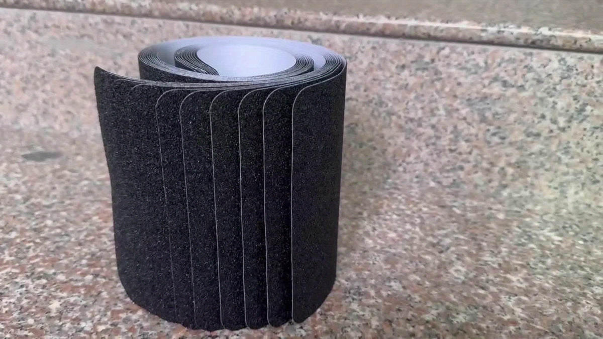 Rolled black anti-slip stair tread strips on gray surface