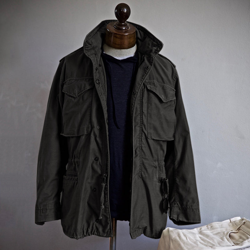 Black men’s field jacket with flap pockets, button front, and drawstring hem