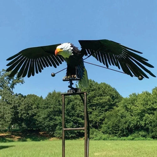 Wind-powered eagle garden stake with dark wings spread on a tall metal frame