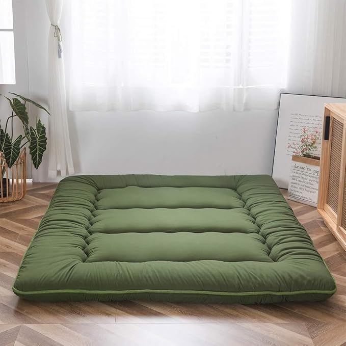 Green foldable floor futon mattress laid flat with cushioned quilted panels