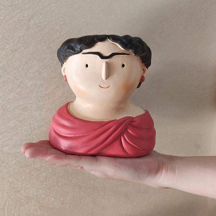 Ceramic face vase with red draped scarf and black hair, gentle smile