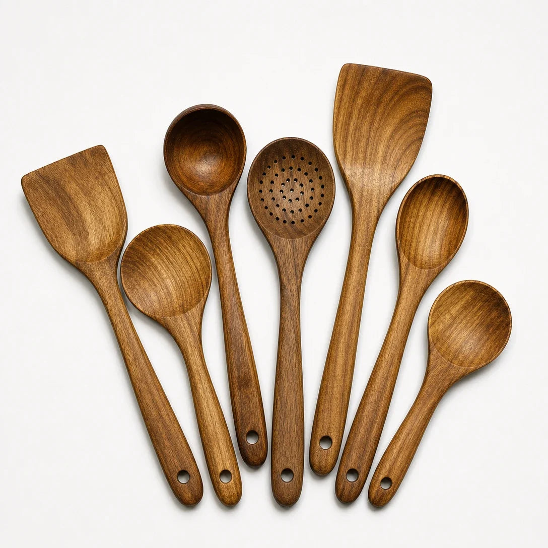 Teak wooden utensil set with 7 spoons and ladles, top view on a white surface