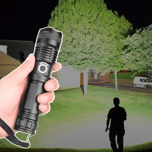 Black rechargeable flashlight held in a hand with a bright beam beam outdoors