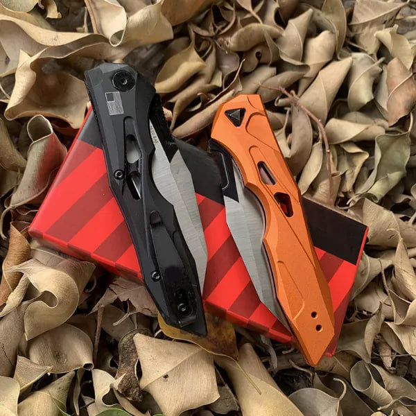 Black and orange auto-fold utility knives with wharncliffe blades, stacked on shavings