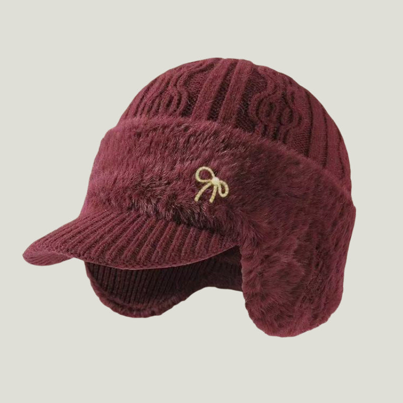 Maroon fuzzy trapper ear flap hat with bow emblem and ribbed brim