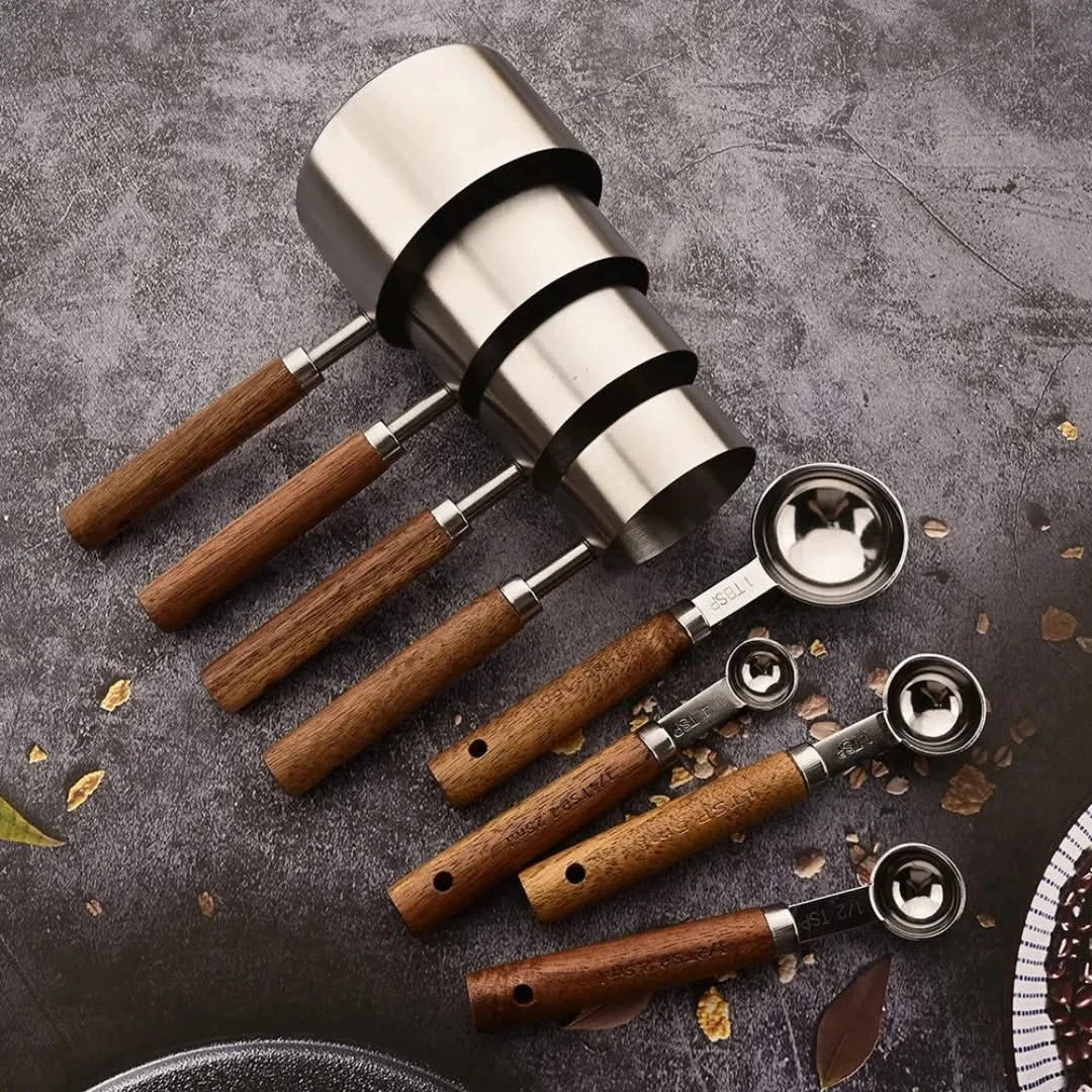 Silver measuring spoon set with wood handles, round cups on long handles.