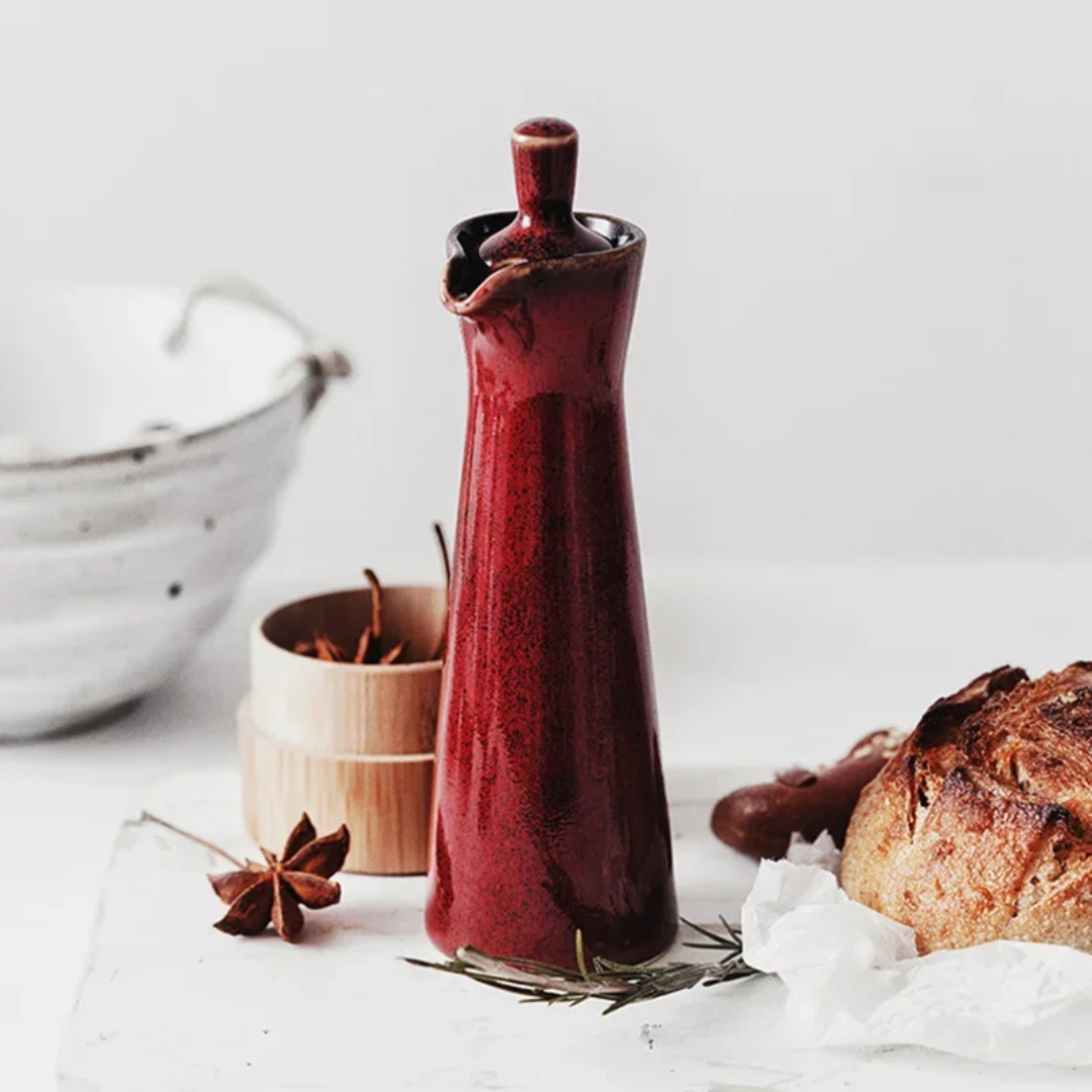 Ceramic oil dispenser, glossy deep red with arched spout and wide base