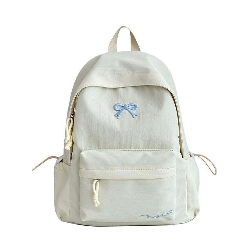 White casual school backpack with blue bow emblem, front pocket, and drawstring pull