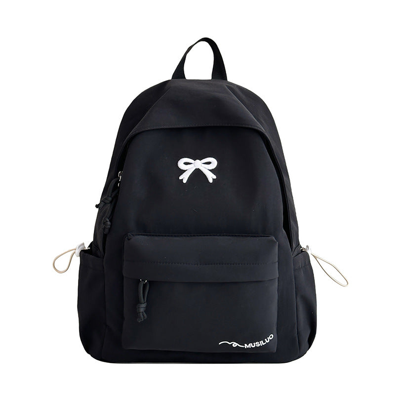 Black casual school backpack with white bow emblem, front pocket, and side drawcords