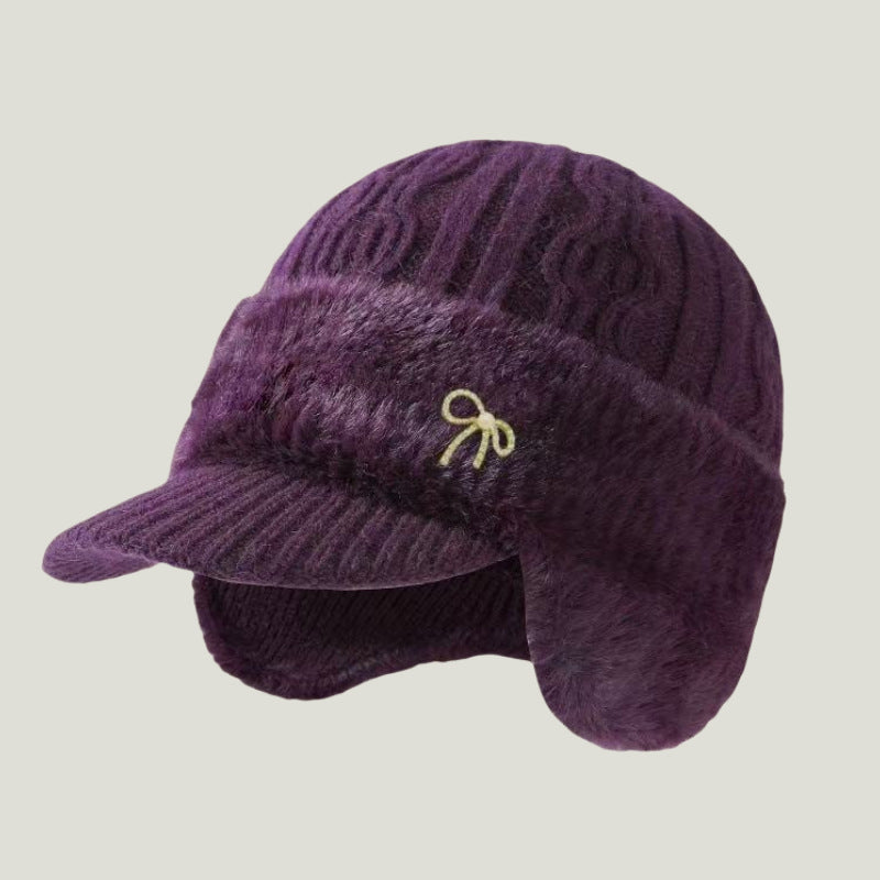 Purple fuzzy trapper ear flap hat with bow emblem and ribbed brim
