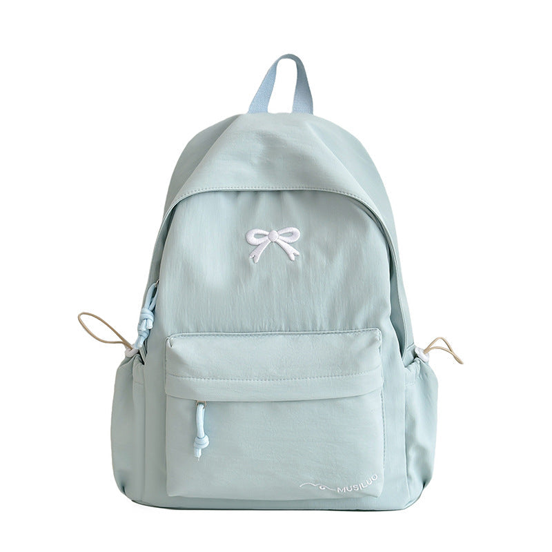 Light blue casual school backpack with bow emblem, front pocket, and side drawcords