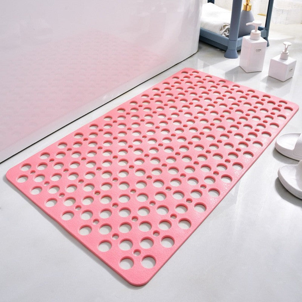 Pink non-slip shower mat with round drainage holes on bathroom floor