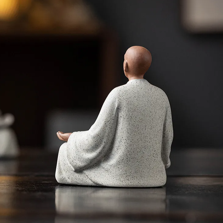 Seated monk statue back view, off-white speckled robe with open hands