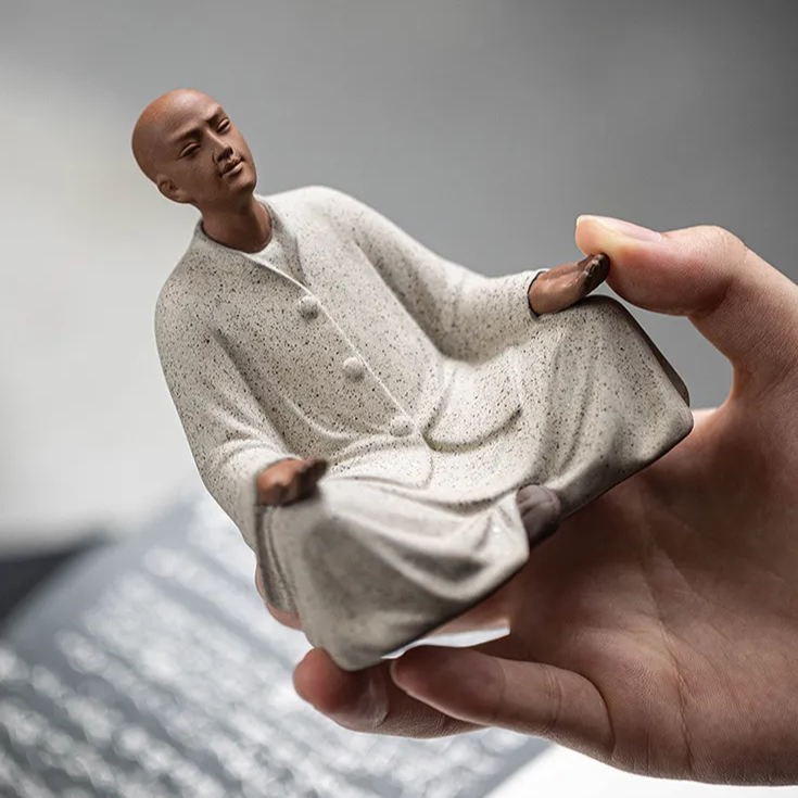 Seated monk statue in off-white speckled robe, side view