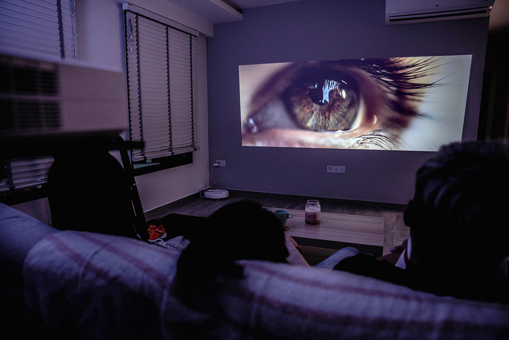 Mini projector projecting a close-up eye image in a dark home theater setting