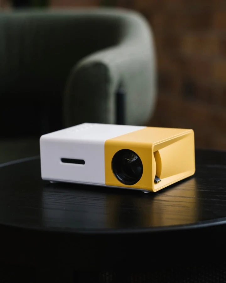 White and yellow mini projector on a table with black front lens