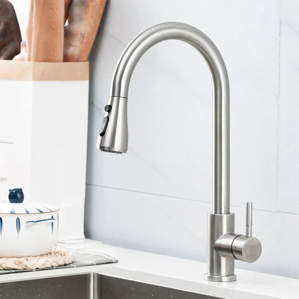 Stainless steel kitchen faucet on a white tiled wall