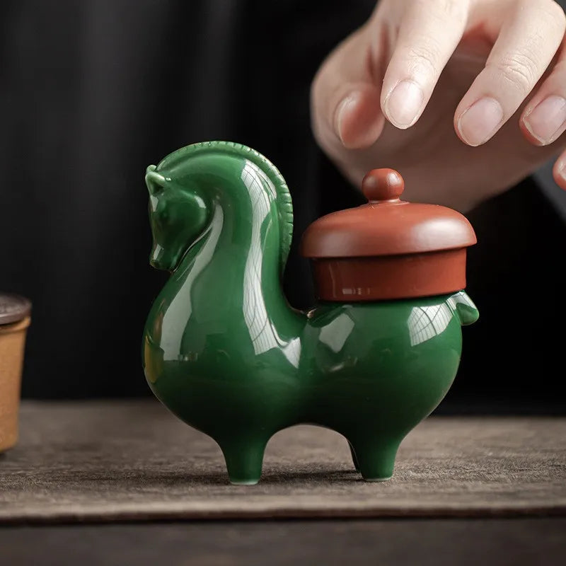 Ceramic horse figurine, dark green glossy glaze, with small brown domed cover.