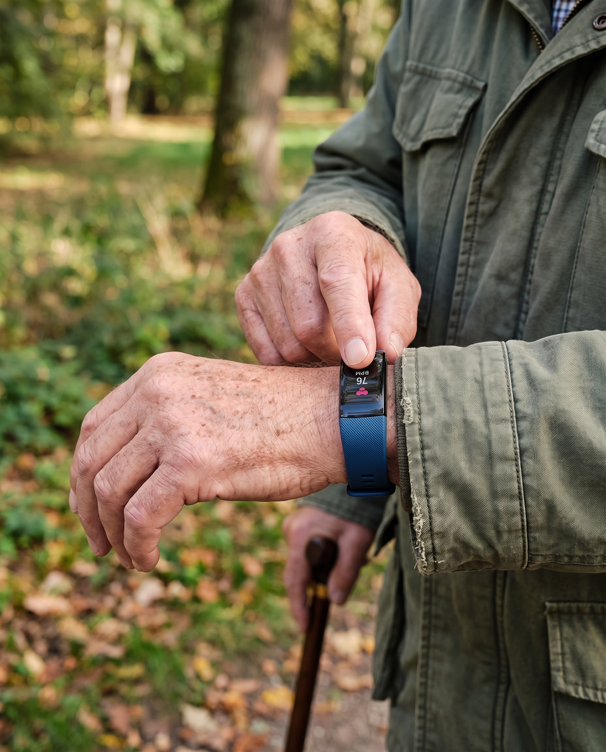 Dark/black smart watch worn on a person’s wrist outdoors while holding a cane