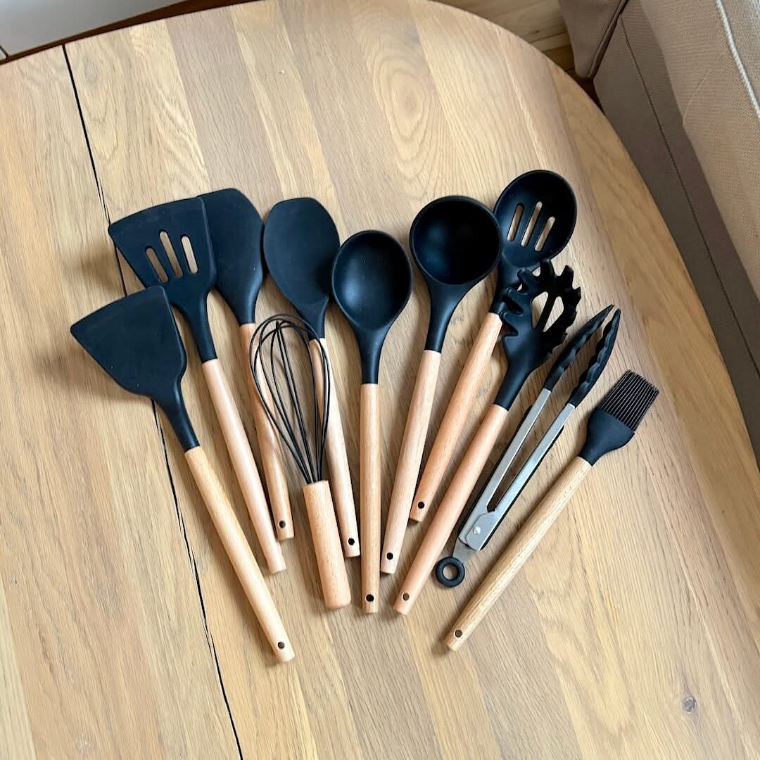 Dark blue silicone cooking utensil set with wooden handles and a whisk