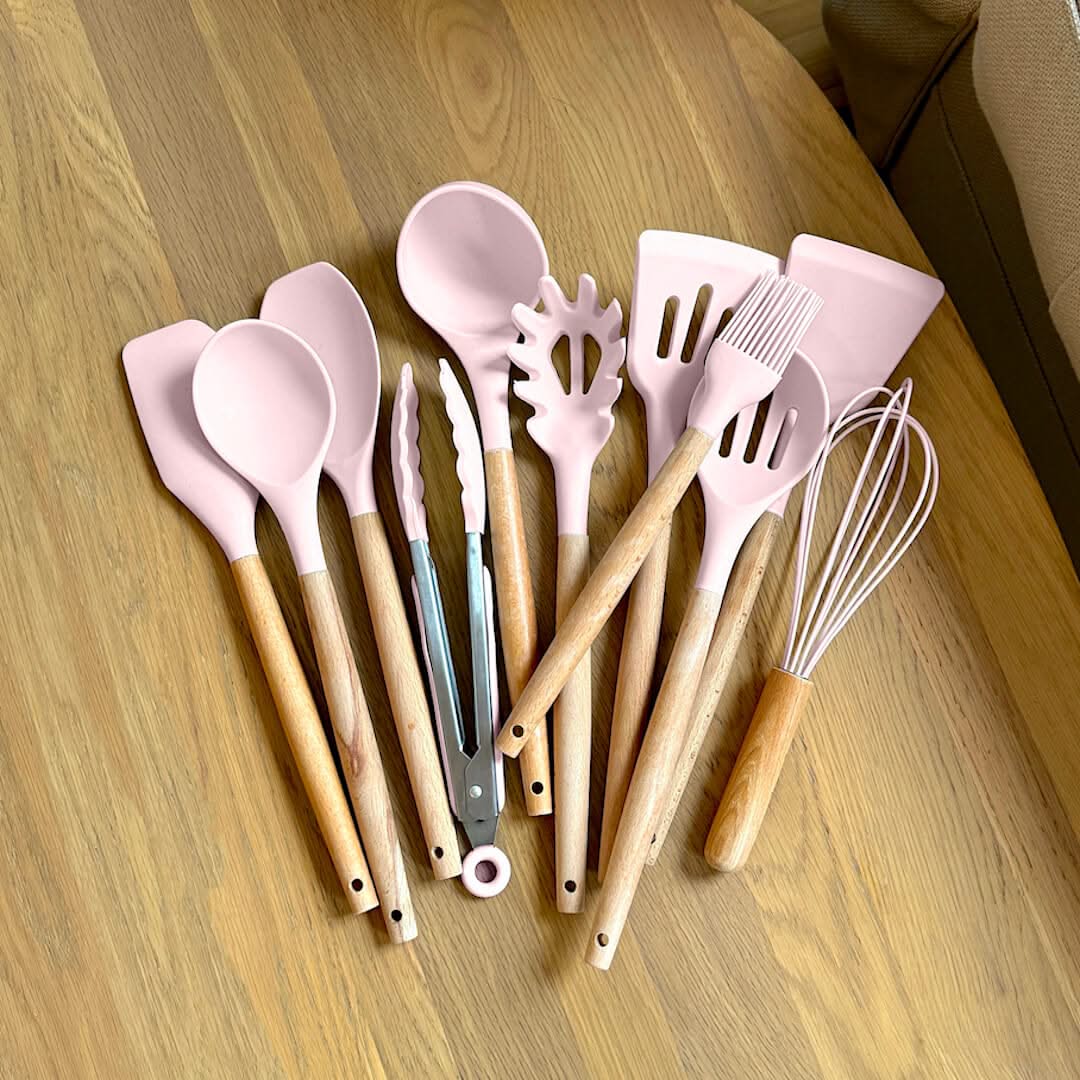 Pink silicone cooking utensil set with wooden handles, heart-shaped and whisk tools