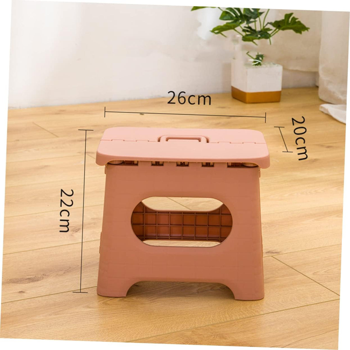 Foldable step stool in pink with oval safety cutout and top carrying handle, measured.