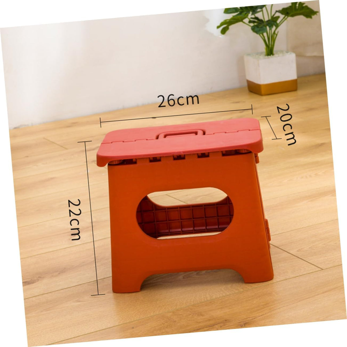 Foldable step stool in orange with oval safety cutout and foldable top carrying handle.