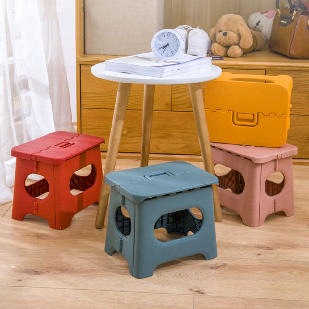 Set of foldable step stools in red, pink, blue, and yellow with oval cutouts.