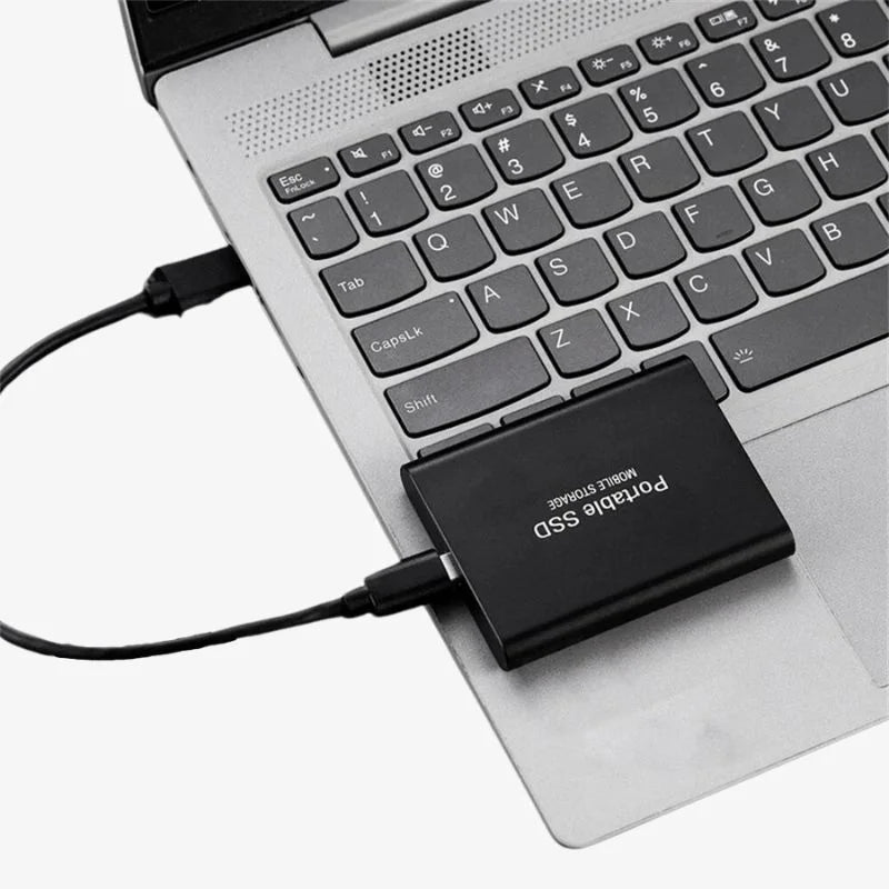 Black portable SSD plugged into laptop using a USB cable