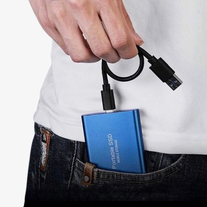 Blue portable SSD connected to cable, held above dark jeans