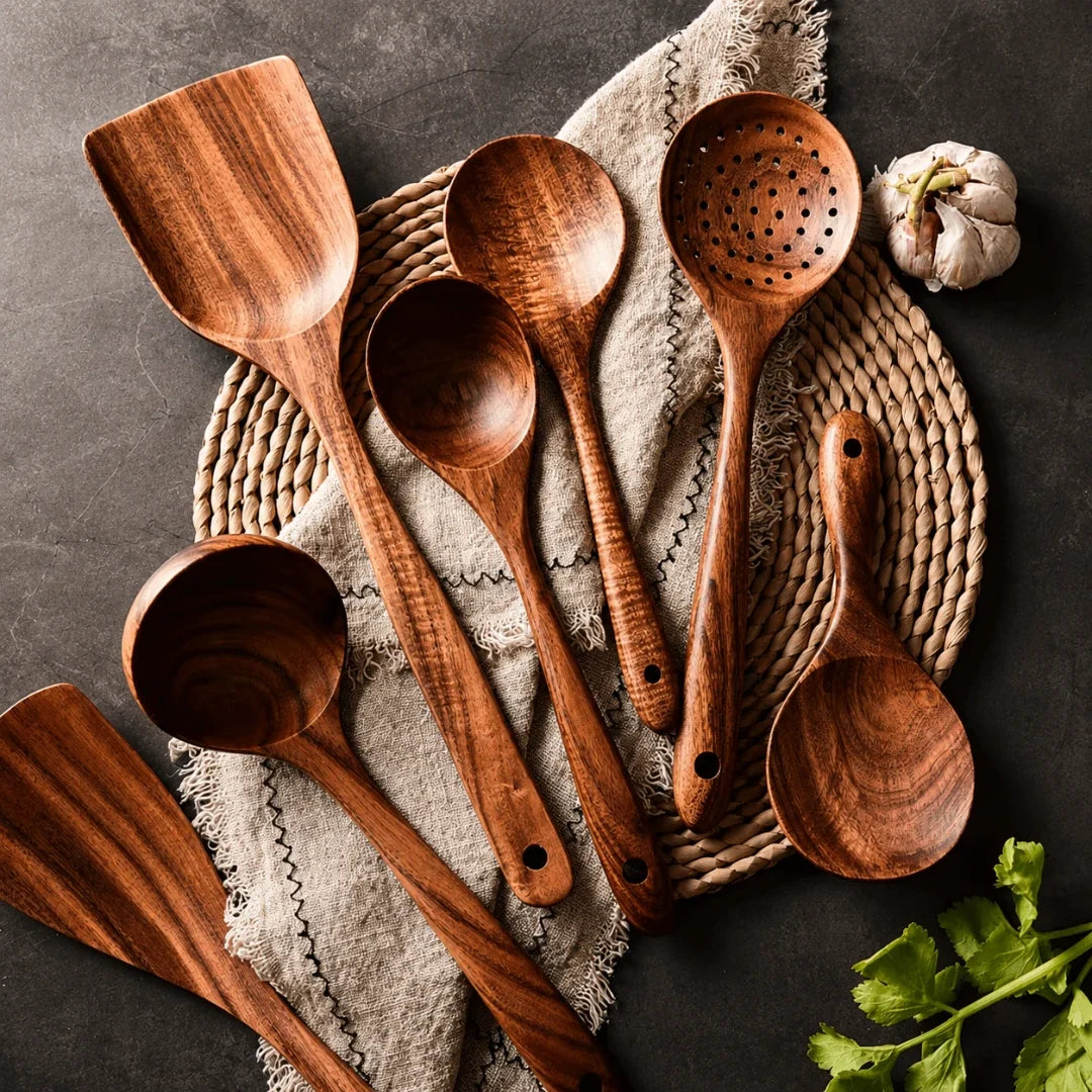Teak wooden cooking utensil set, assorted spoons and spatulas on a folded cloth