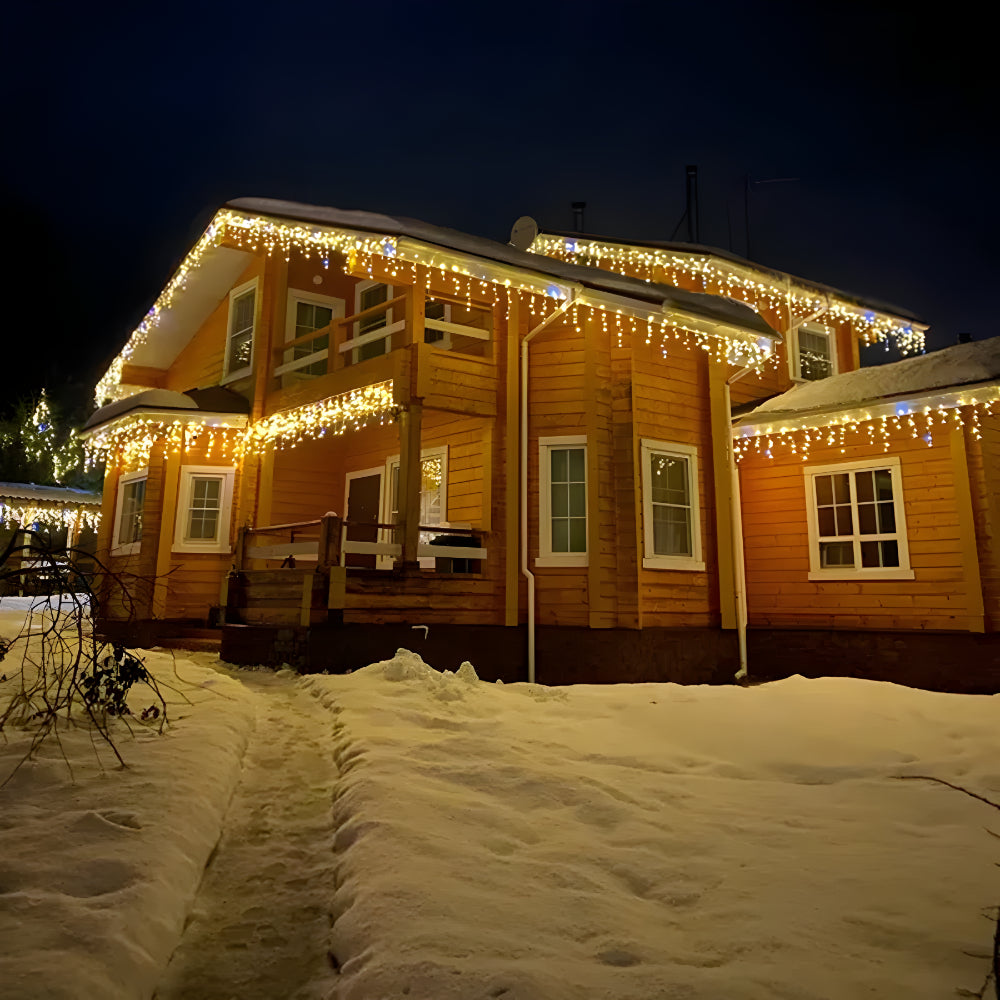 Wooden house decorated with string lights at night in a snowy landscape