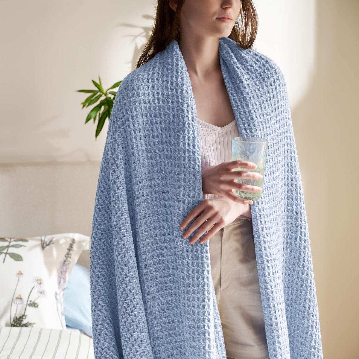 Cotton waffle-weave cooling blanket in light blue, worn draped over shoulders