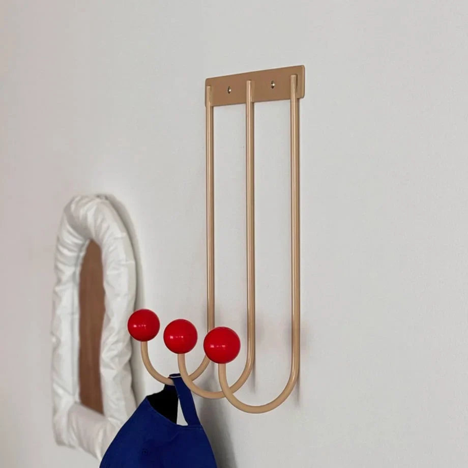 Metal wall hook rack with three curved hooks and red ball knobs, blue bag hanging