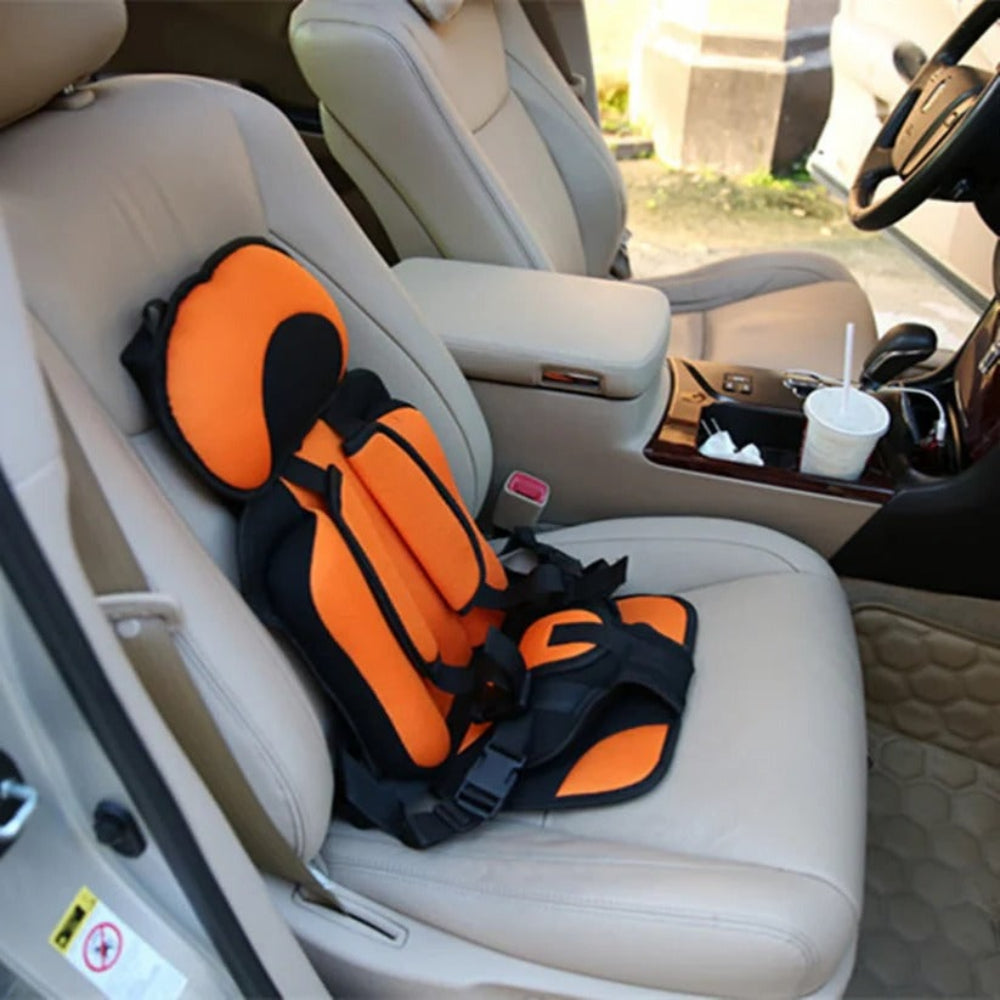 Orange kids travel car seat safety booster with black straps on a vehicle seat