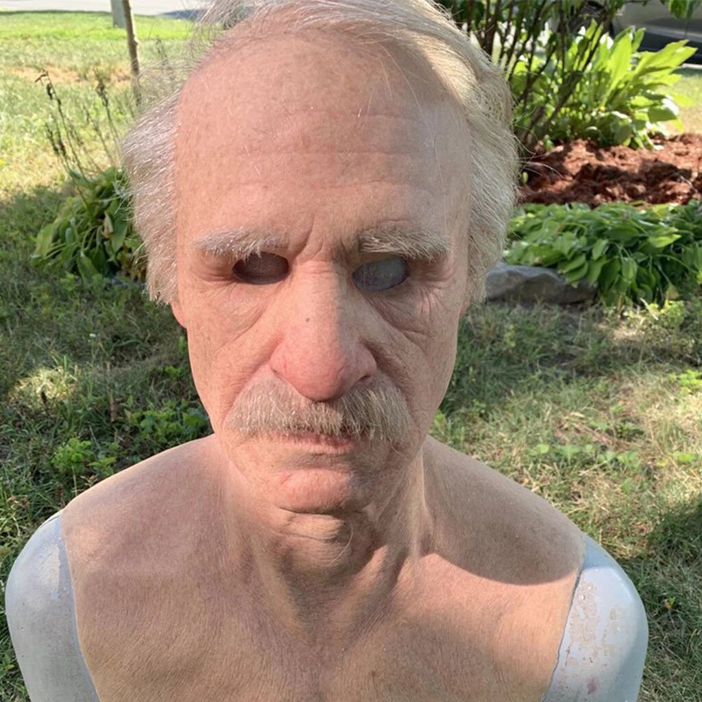 Realistic latex Halloween mask close-up with bald head, deep wrinkles, and gray mustache