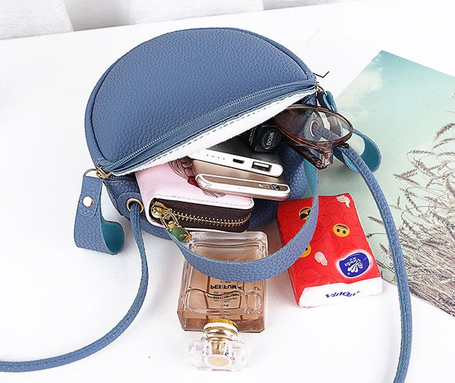 Blue round crossbody bag with open zipper showing interior and crossbody strap