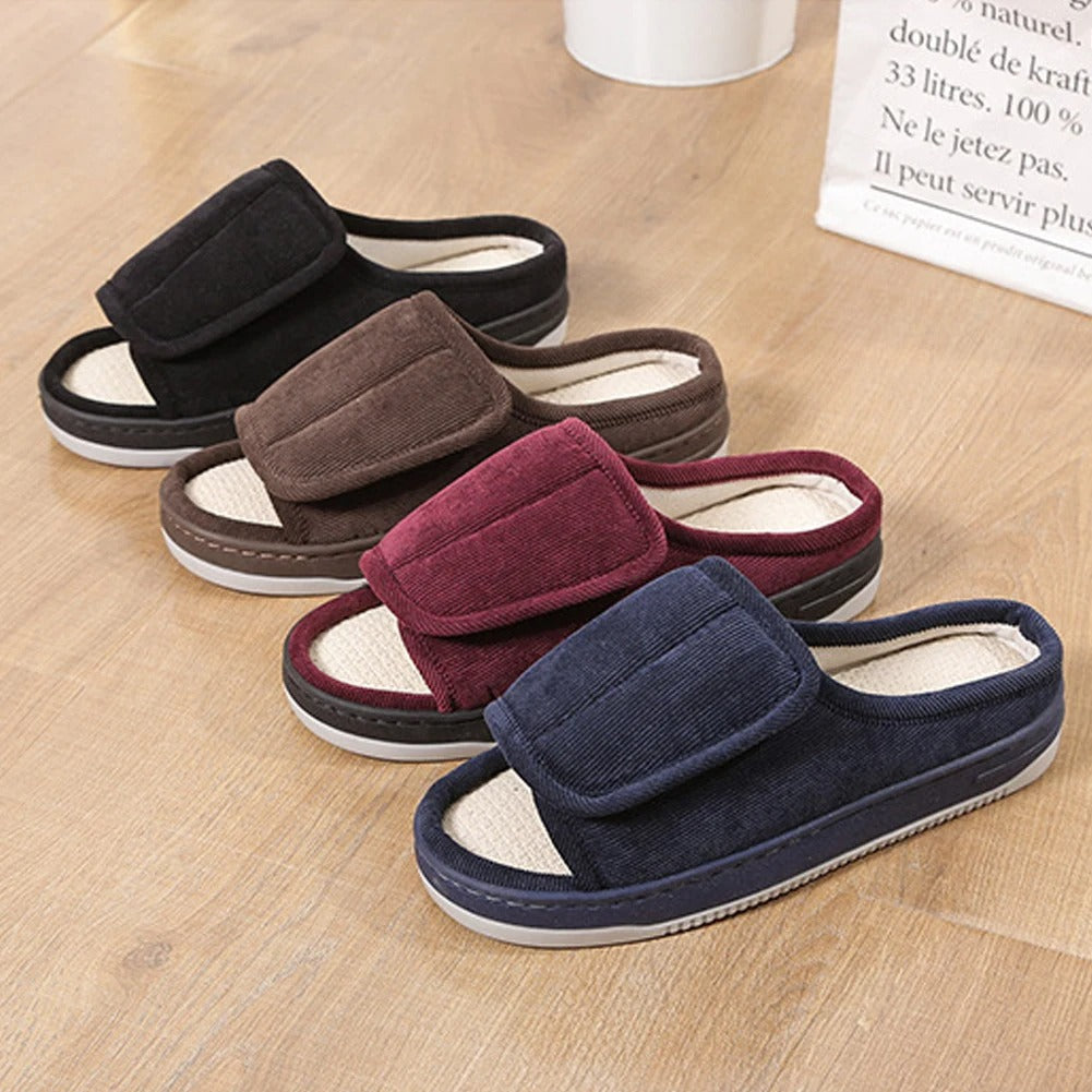 Four pairs of slippers in black, brown, red, and blue on a wooden floor.