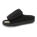 Black slip-on shoe with velcro strap on a white background