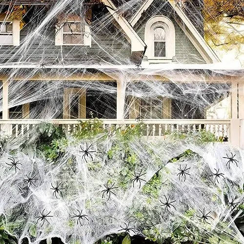Spider web decoration stretched across a porch railing with white strands and black spiders