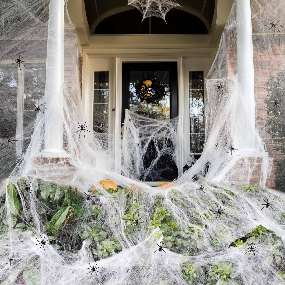 Outdoor spider web decoration draped over an entryway with white web and black spiders
