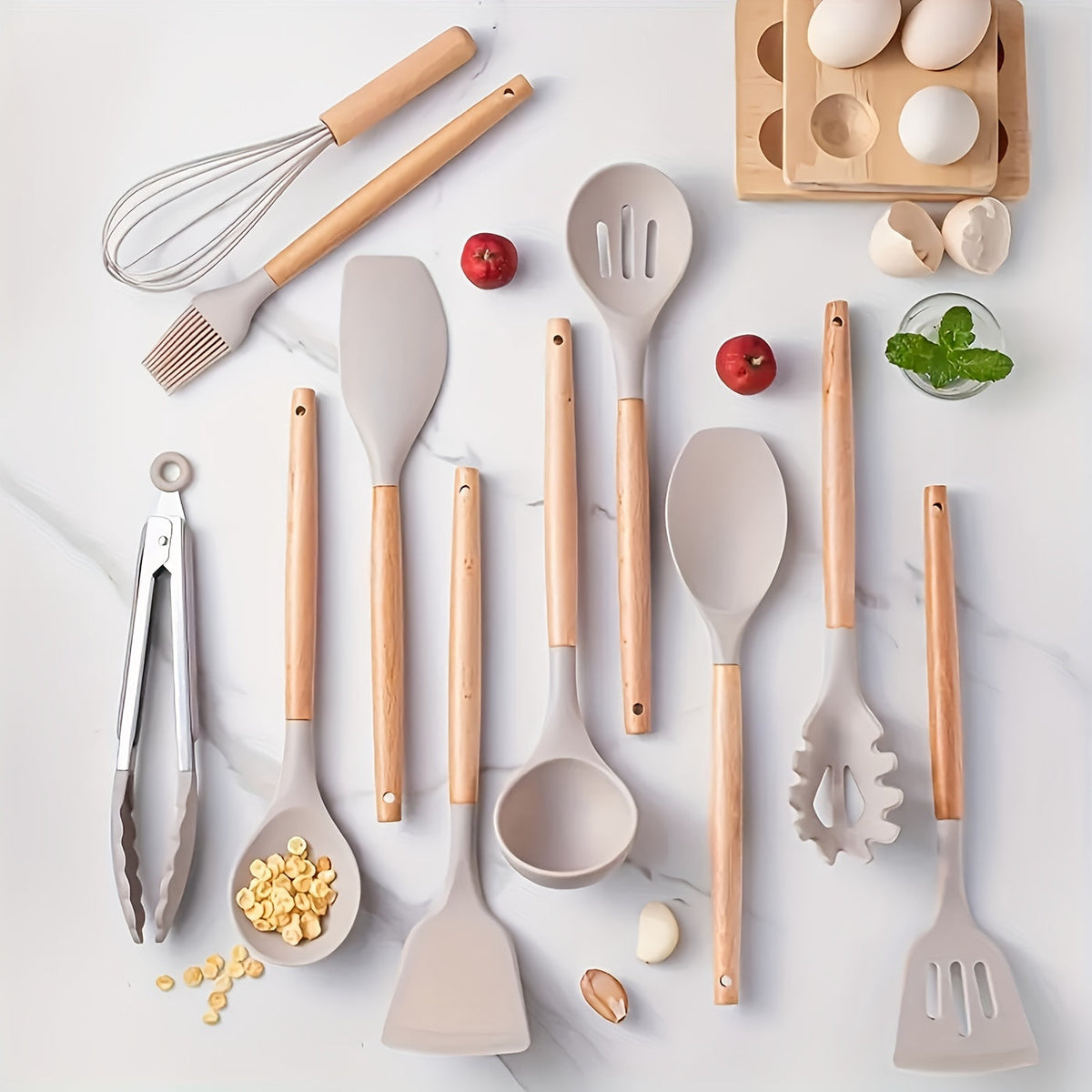 Silicone utensil set with light wood handles, white heads, and a visible whisk and spatula.
