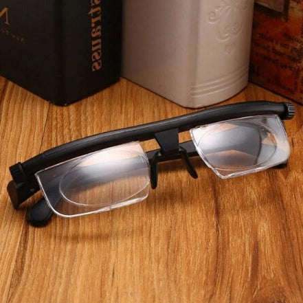 Black adjustable reading glasses with clear lenses lying on a wooden surface