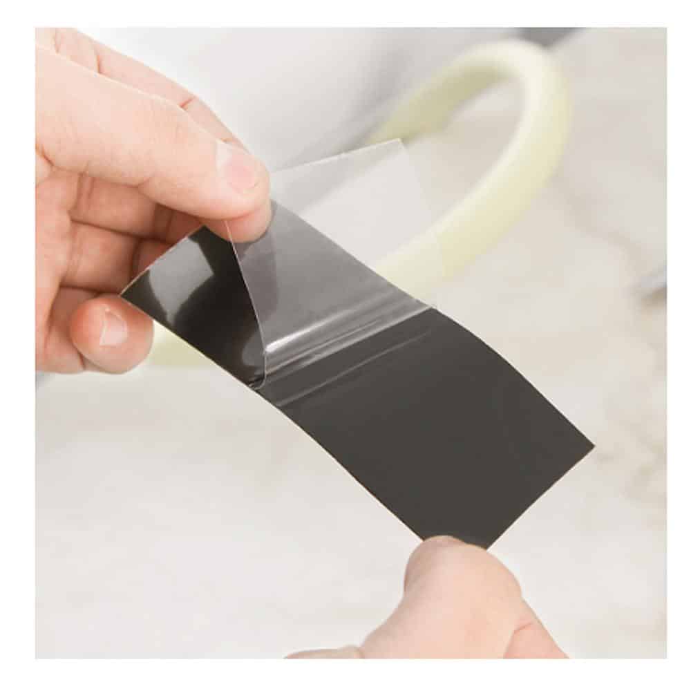 Black rubber repair tape strip being pressed onto surface by hands