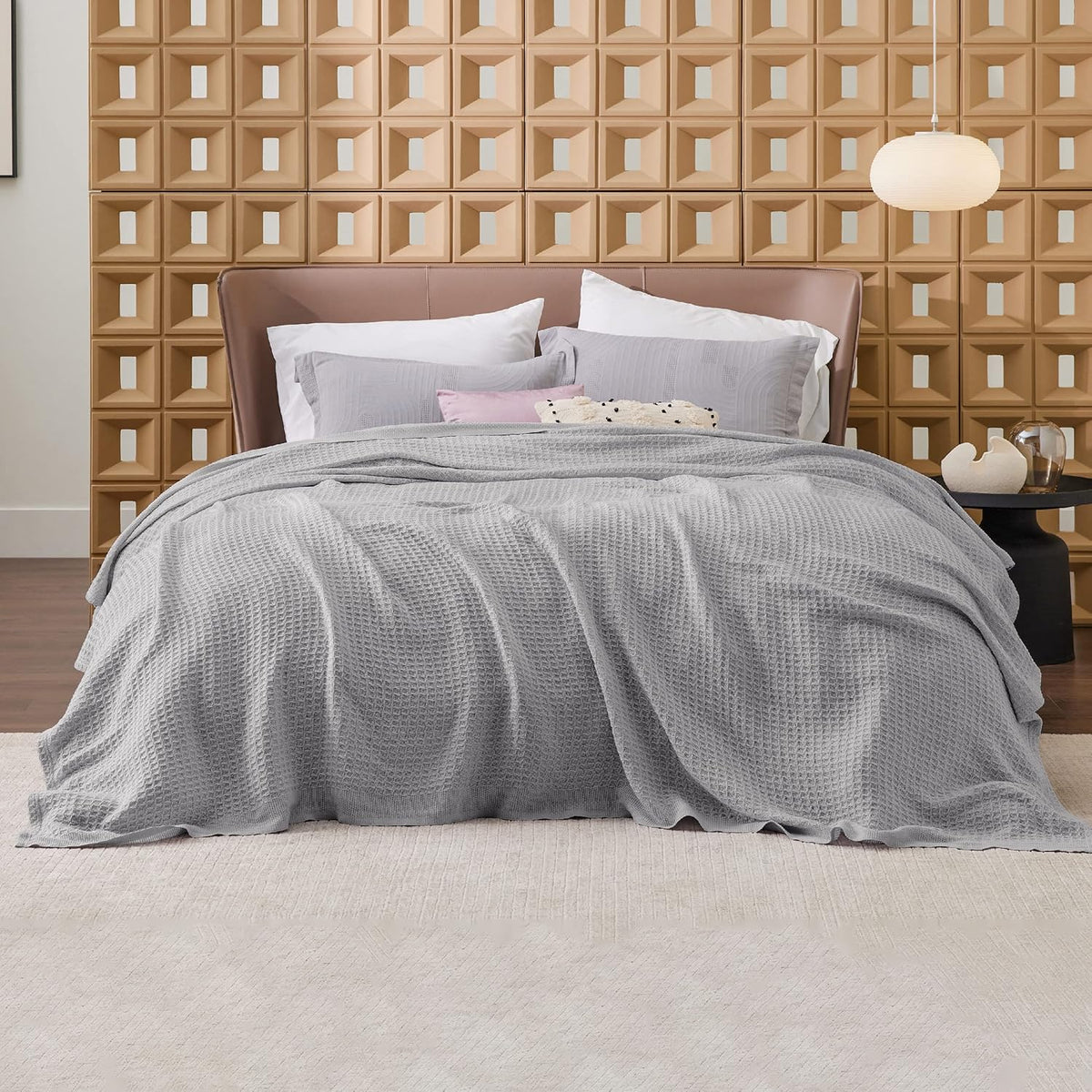 Gray cotton waffle-weave cooling blanket on a bed, softly rumpled with waffle texture.