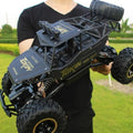 Black remote control crawler truck with large tread tires and rugged roll frame