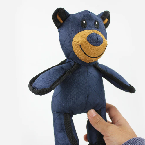 Blue bear plush chew toy with tan muzzle and black ears, held by a hand.
