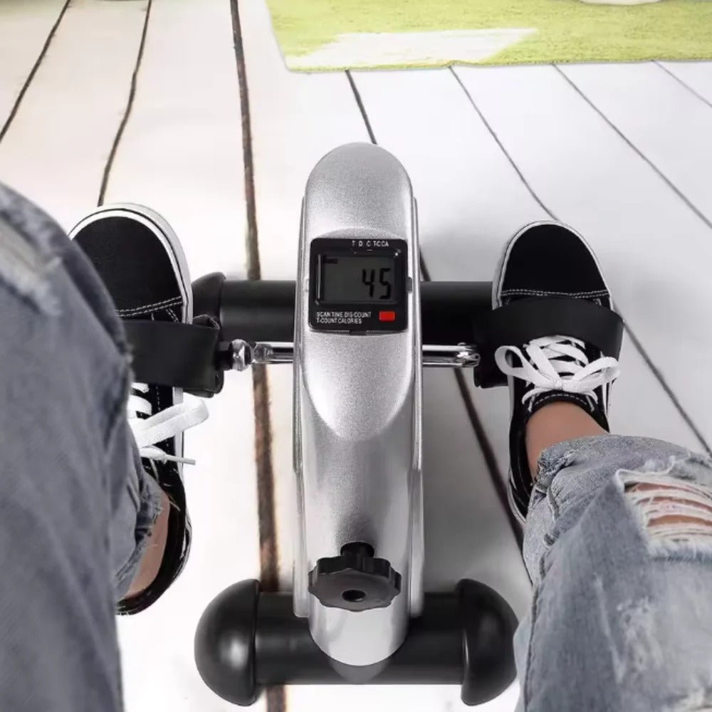 Silver under-desk pedal trainer with LCD display and curved pedals under shoes