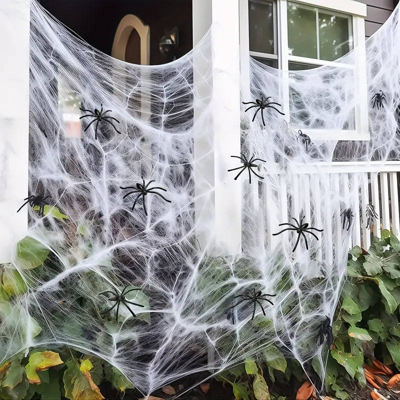 Spider web decoration with white netting, black spiders, and draped strands by a window